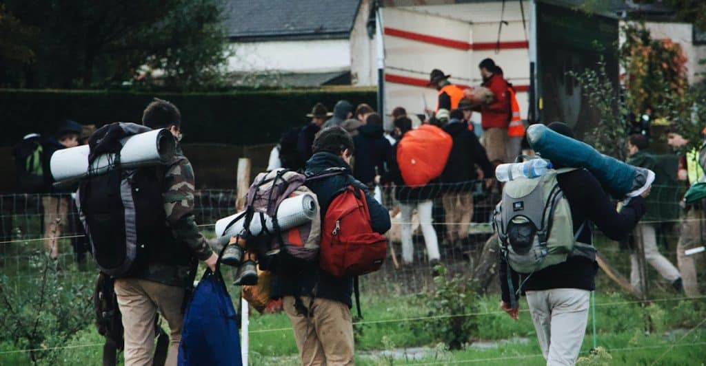 A group of people with backpacks walking outdoors in a rural setting.