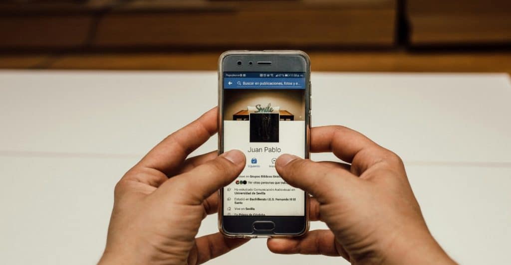 Two hands holding a smartphone displaying a dating app profile.