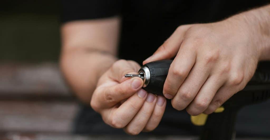 Close up of hands adjusting a drill bit on a cordless drill.