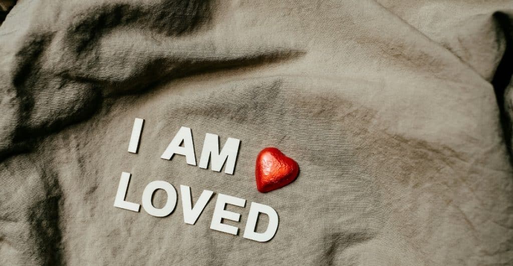 The phrase "I AM LOVED" spelled out on a piece of textured fabric with a red heart.