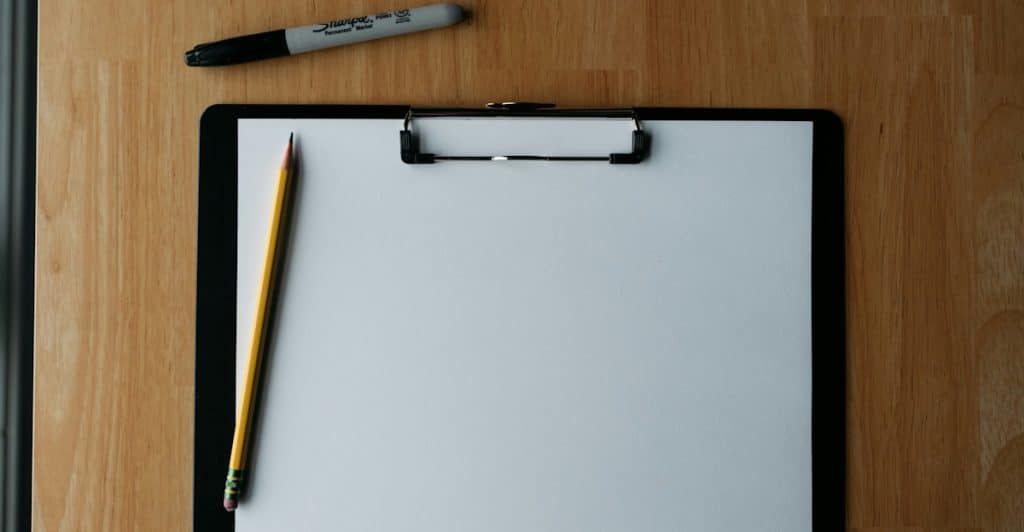 Clipboard with a blank sheet of paper and a sharpened pencil.