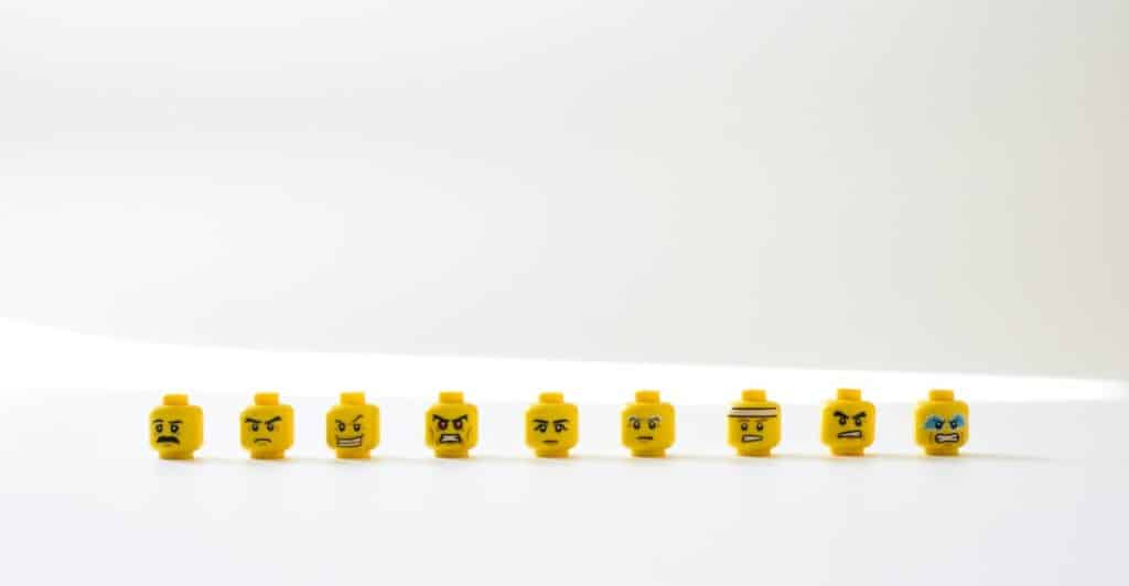A line of yellow Lego heads with different emotional expressions against a white background.