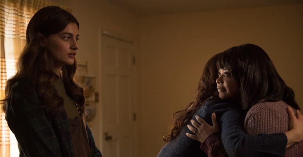 A Girl watching a woman and another girl embrace.