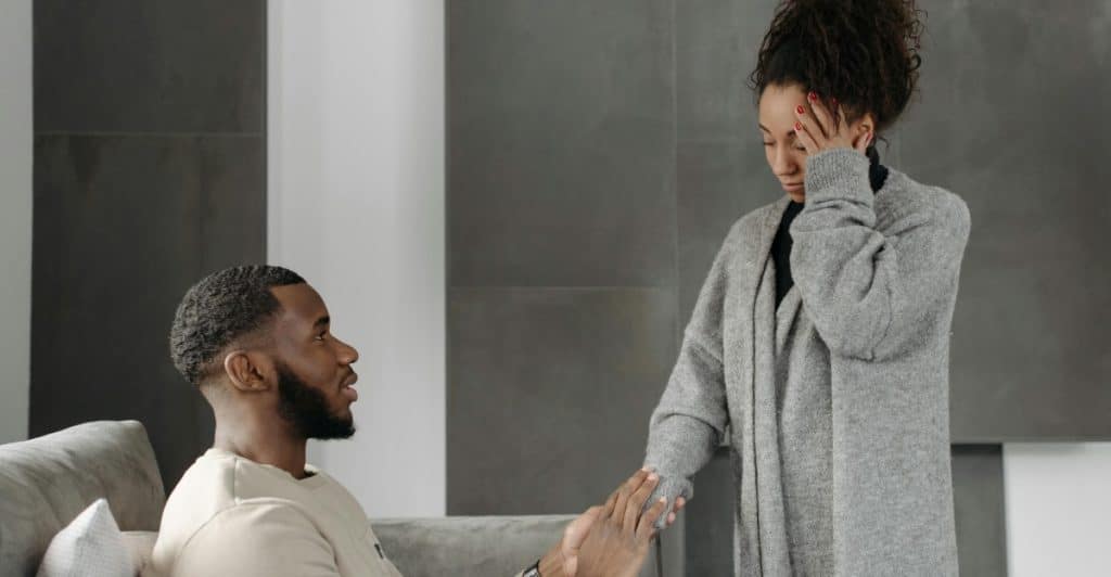 A man comforting a distressed woman on a couch.