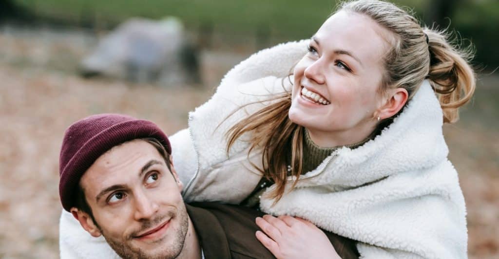 A man giving a woman a piggyback ride outdoors.