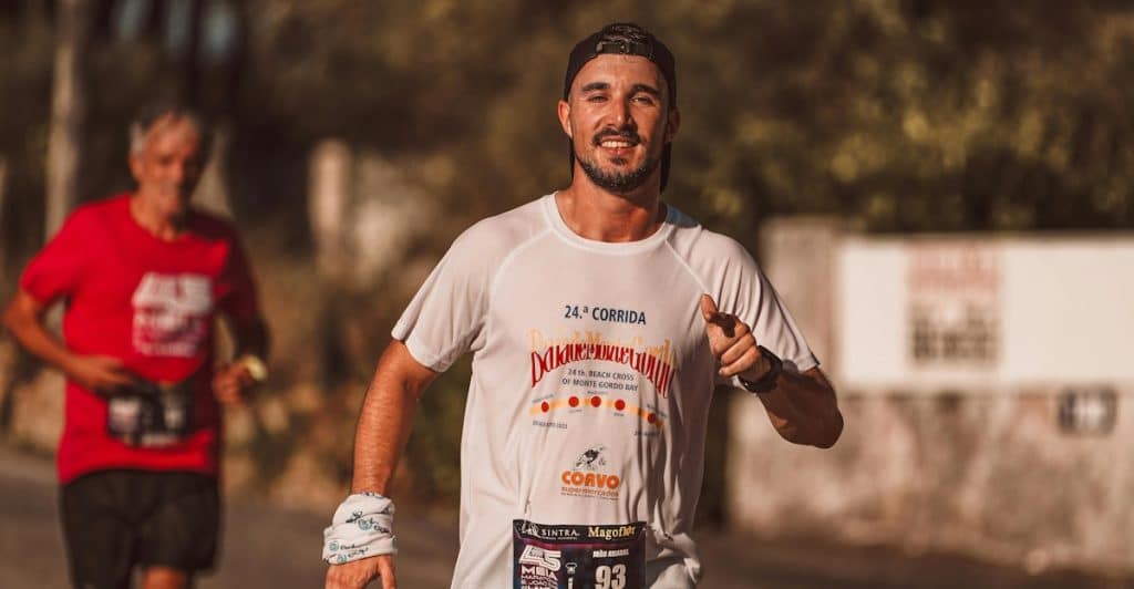 A man running in an outdoor race, wearing a race bib and athletic attire.