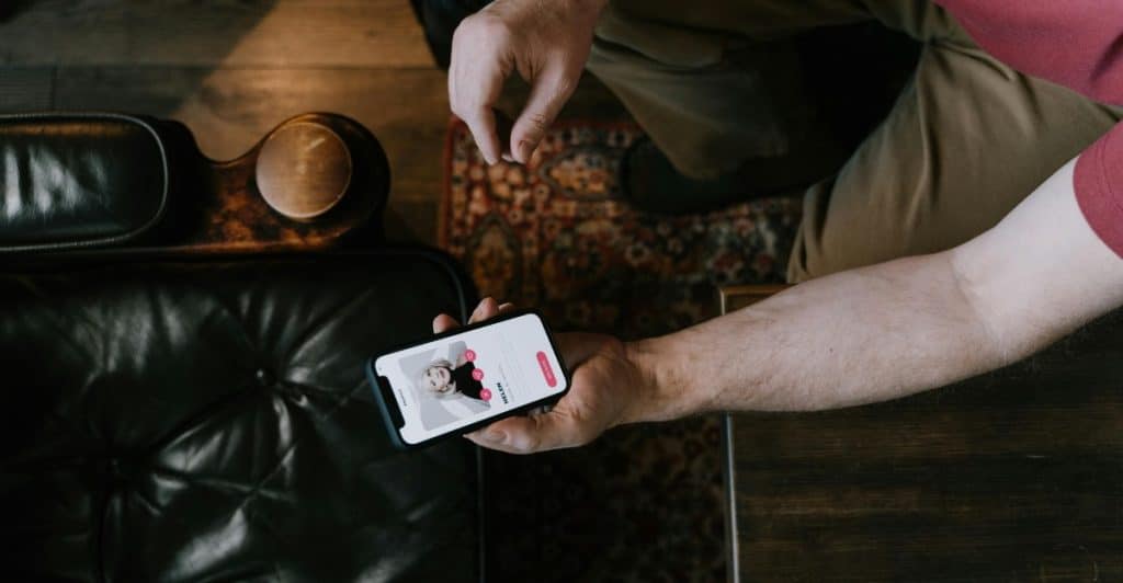 A close-up shot of a man's hands holding a smartphone while using a dating app.A close-up shot of a man's hands holding a smartphone while using a dating app.