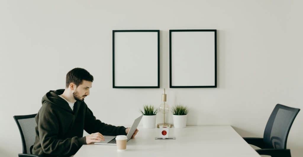 A man working on a laptop at a desk in a minimalist office setting.
