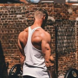 A man lifting weights outdoors, viewed from the back, showing his muscular shoulders and back.