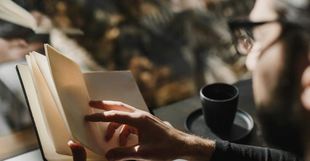 A man journals in a peaceful space, taking steps to reflect and unlearn reactive anger.