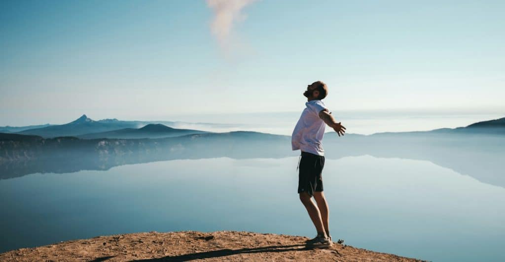 A man happy and calm beside a body of water.
