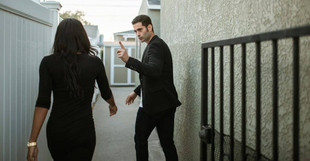 A man talking to a woman walking away from him down an alley.