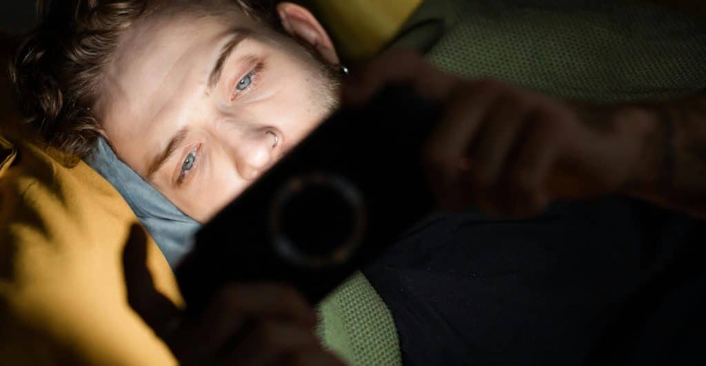 A man lying down and playing games on a PSP.