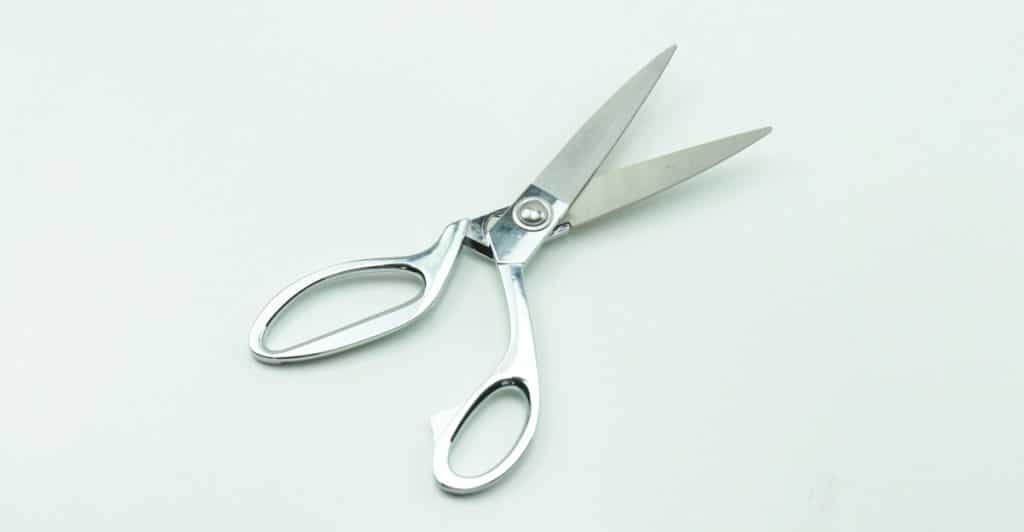 Open stainless steel medical scissors on a white background.