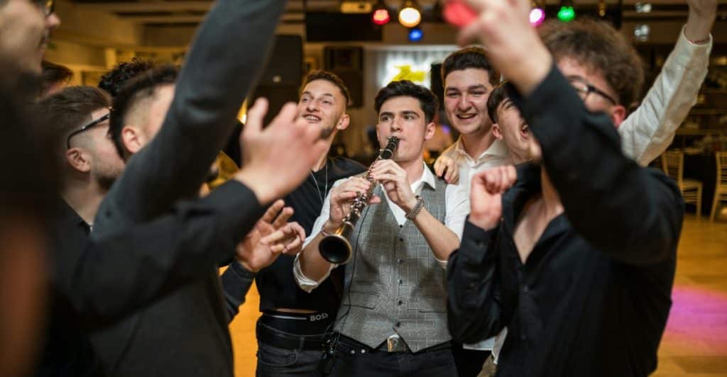 A group of men celebrating around a man playing a clarinet at what appears to be a party or event.