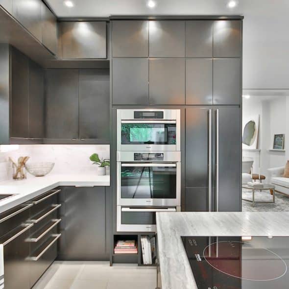 A modern kitchen with dark cabinetry, stainless steel appliances, and an island with a stovetop.
