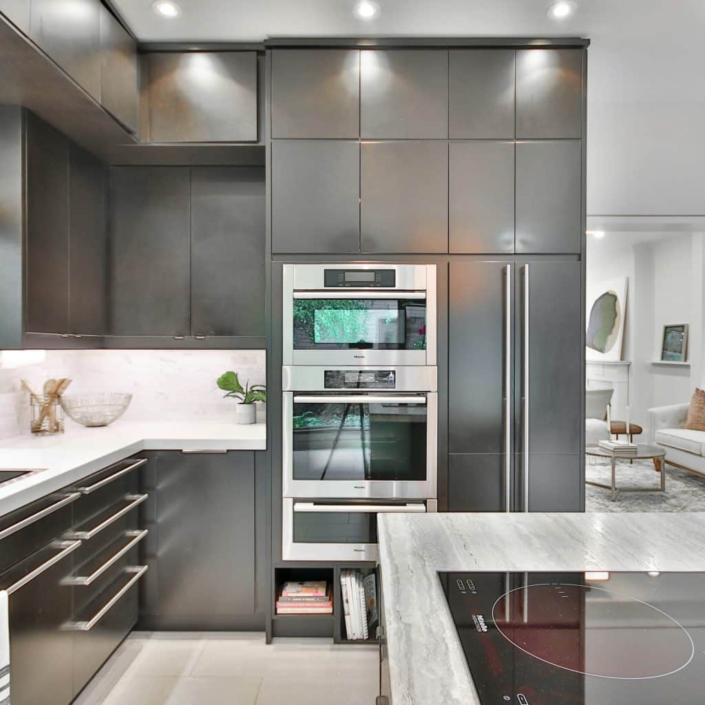 A modern kitchen with dark cabinetry, stainless steel appliances, and an island with a stovetop.