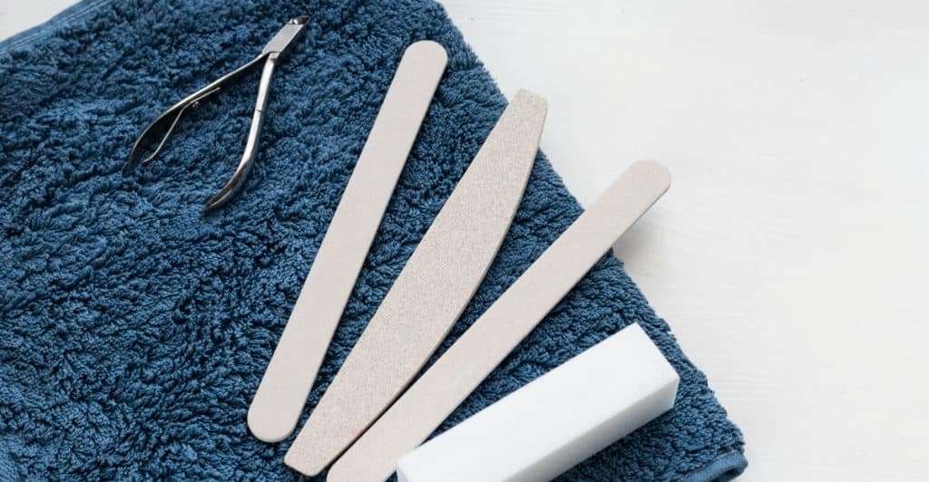Nail clippers and several nail files arranged on a folded blue towel.