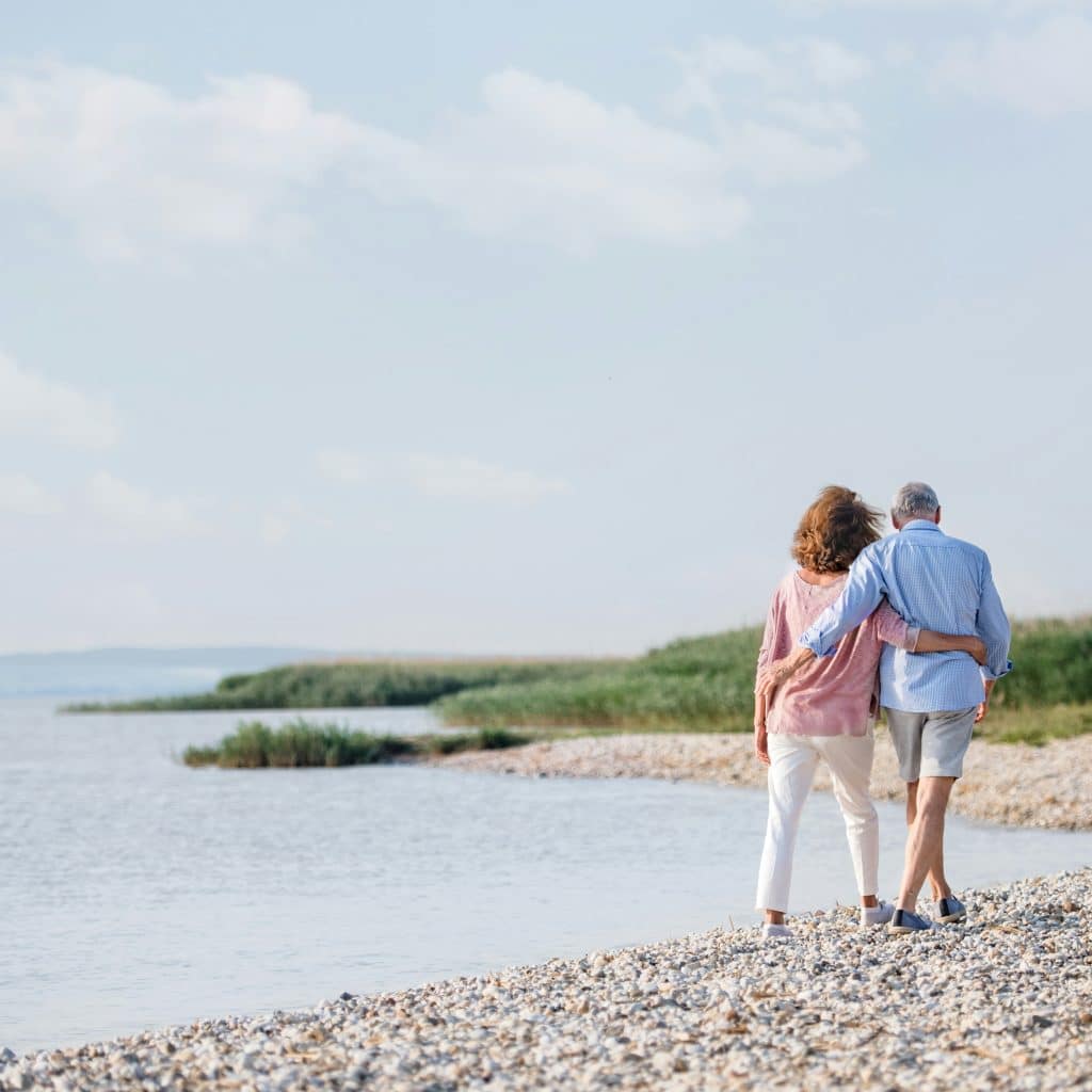 A photo of an old couple walking on the beach.