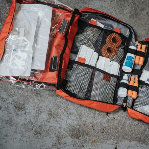 Open orange first aid kit with various compartments and supplies.
