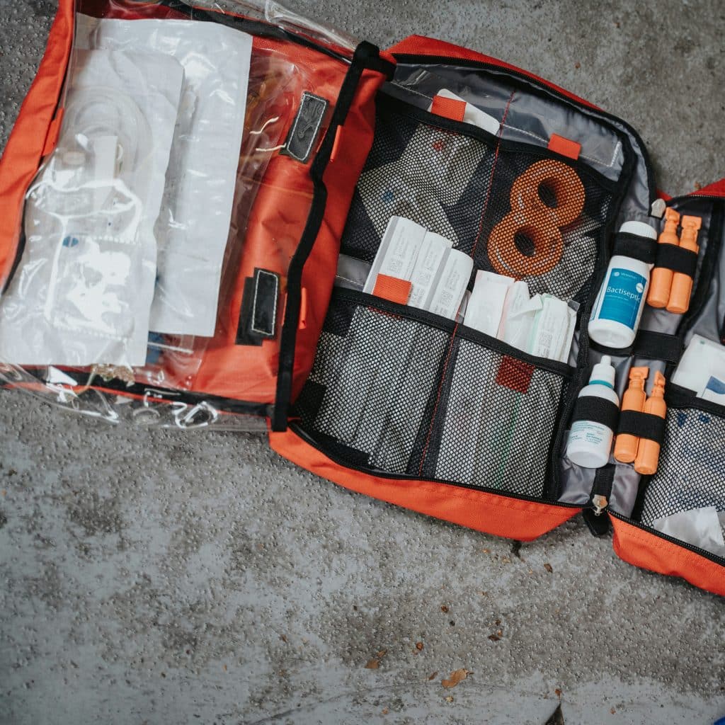 Open orange first aid kit with various compartments and supplies.