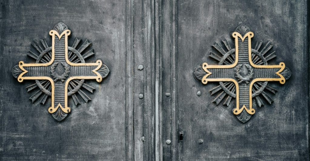 A set of dark, ornate metal doors adorned with two decorative crosses.