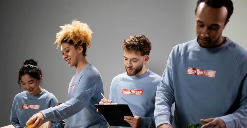 Four people volunteering, sorting food items and putting them into boxes.