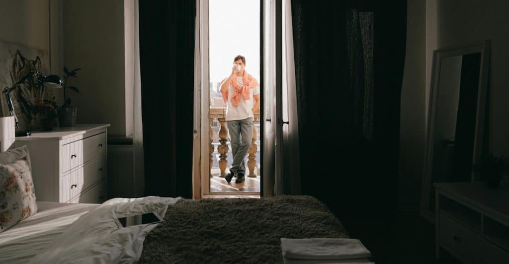 A person is standing in a doorway with bright sunlight coming through.