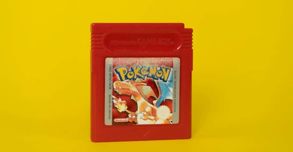 A red Nintendo Game Boy cartridge for the game Pokémon Red, featuring Charizard on the label, against a yellow background.