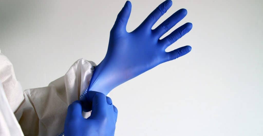 Person pulling on blue disposable medical gloves.