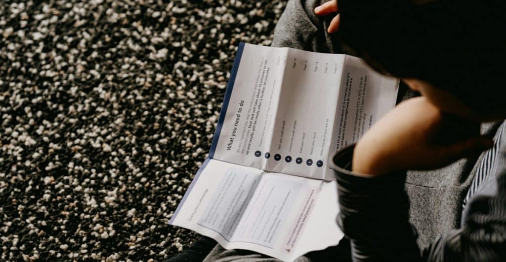 Person reading a printed first aid instruction manual.