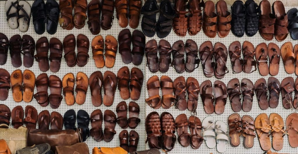 A high-angle view of a display of numerous sandals and bags in various shades of brown and black.