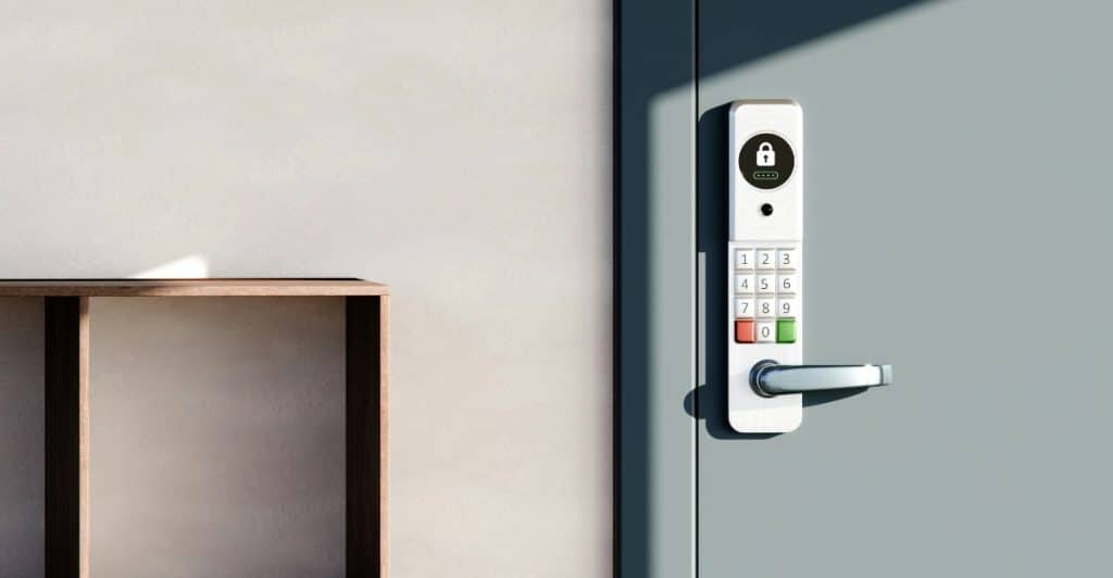 A white smart door lock with a keypad on a gray door.