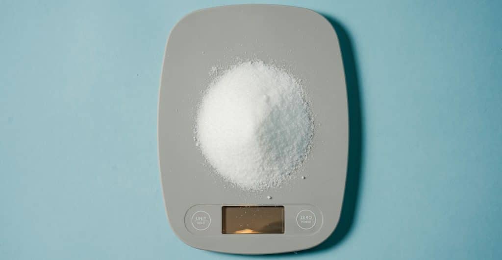 A gray smart kitchen scale with a pile of white powder on it.
