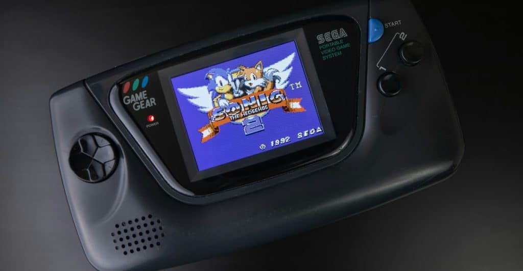 A black Sega Game Gear handheld console displaying Sonic the Hedgehog 2 on its screen.