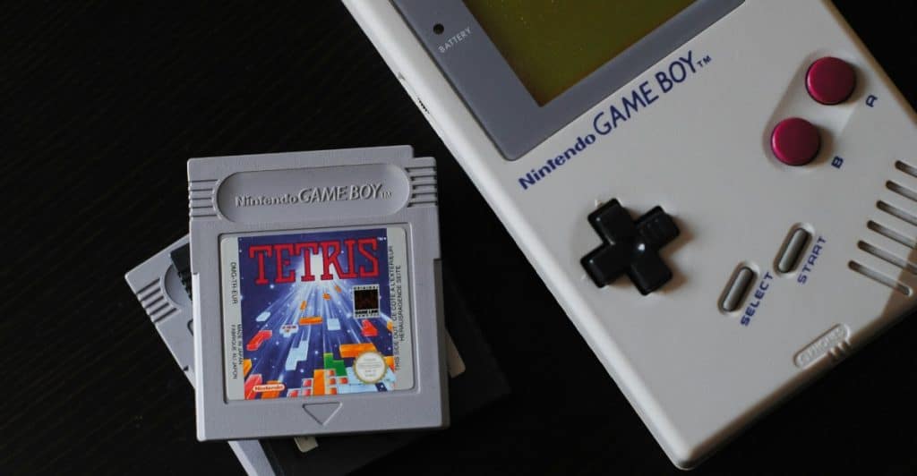 A Tetris game cartridge for the Nintendo Game Boy next to a grey Nintendo Game Boy console.