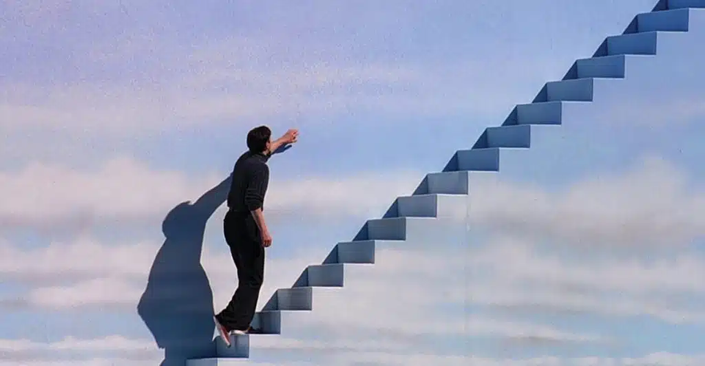 A man walking up some stairs against a cloud wallpaper.