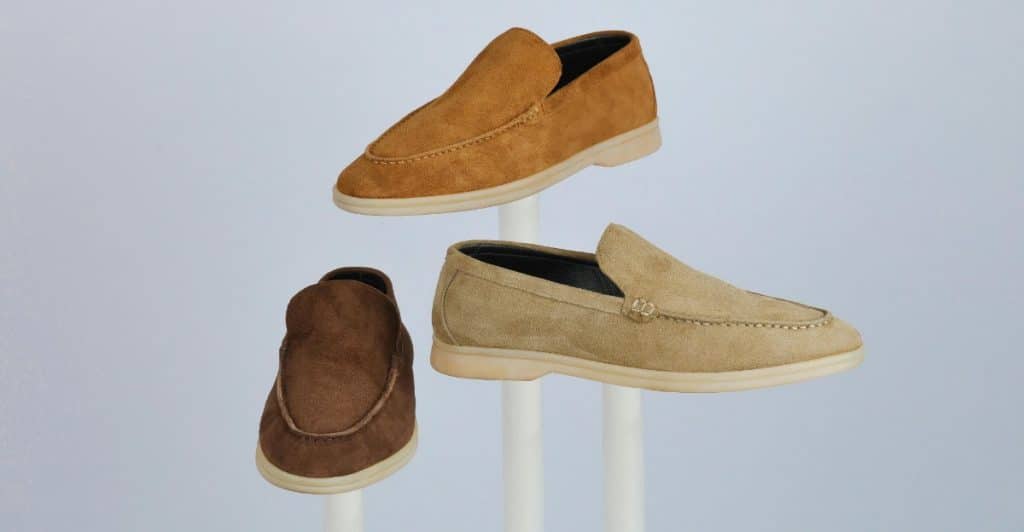 Three different colored suede loafers, one brown, one tan, and one lighter tan, displayed on white stands.