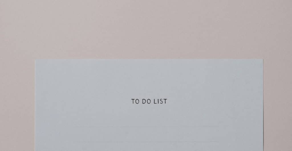 A piece of paper with "TO DO LIST" at the top and blank lines below, on a light pink surface.