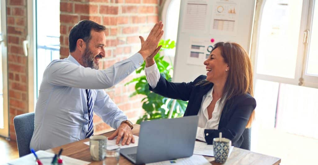 Man and woman high-fiving at work.
