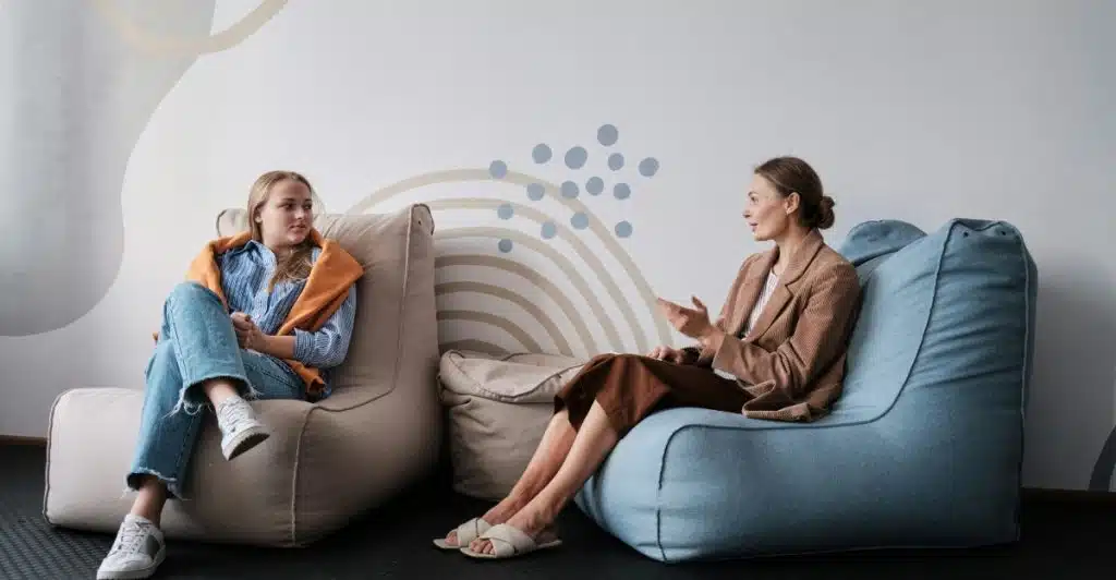 Two women sitting on beanbag chairs, engaged in conversation.