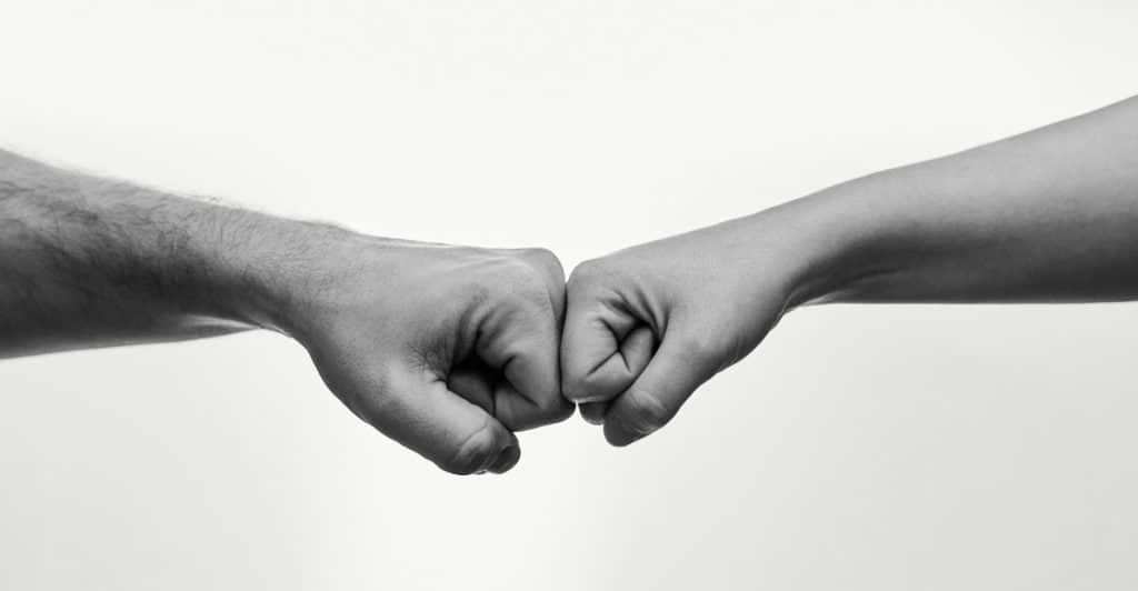 Two arms with fists bumping against each other in a black and white image