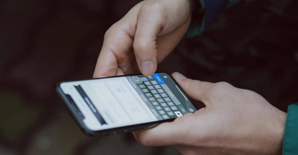  Close-up of hands typing on a smartphone keyboard.