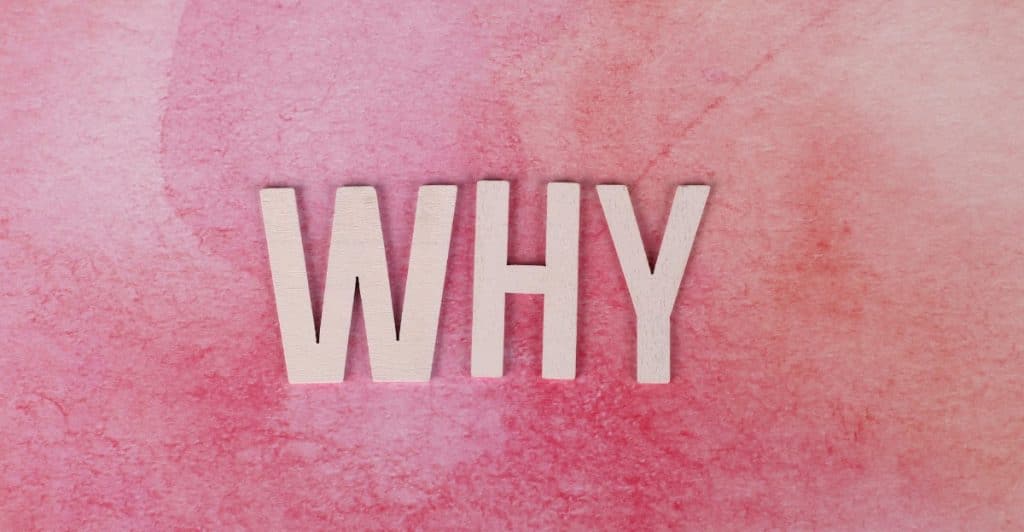 Wooden letters spelling "WHY" on a textured pink background.