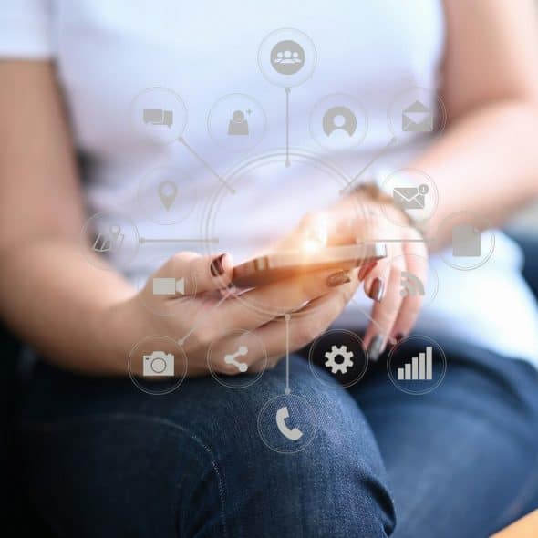 A woman holding a smartphone with a circular overlay of various app icons surrounding it.