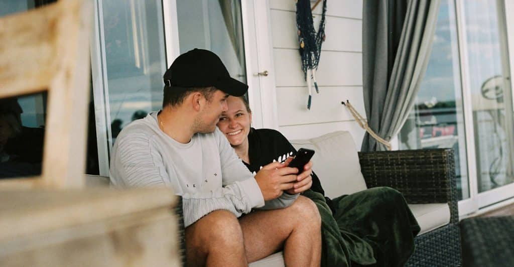 A couple relaxing on a patio with a phone in the man’s hand.