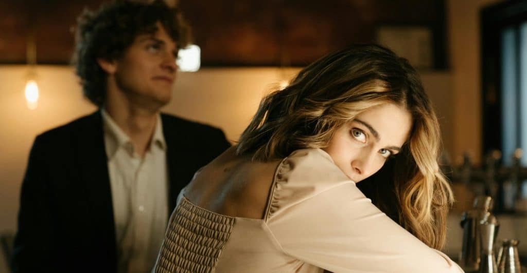 A woman looking over her shoulder while a man sits across the counter at a bar.