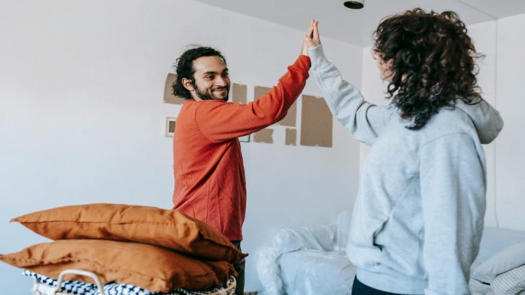A couple celebrating a financial milestone with a high five and a smile.
