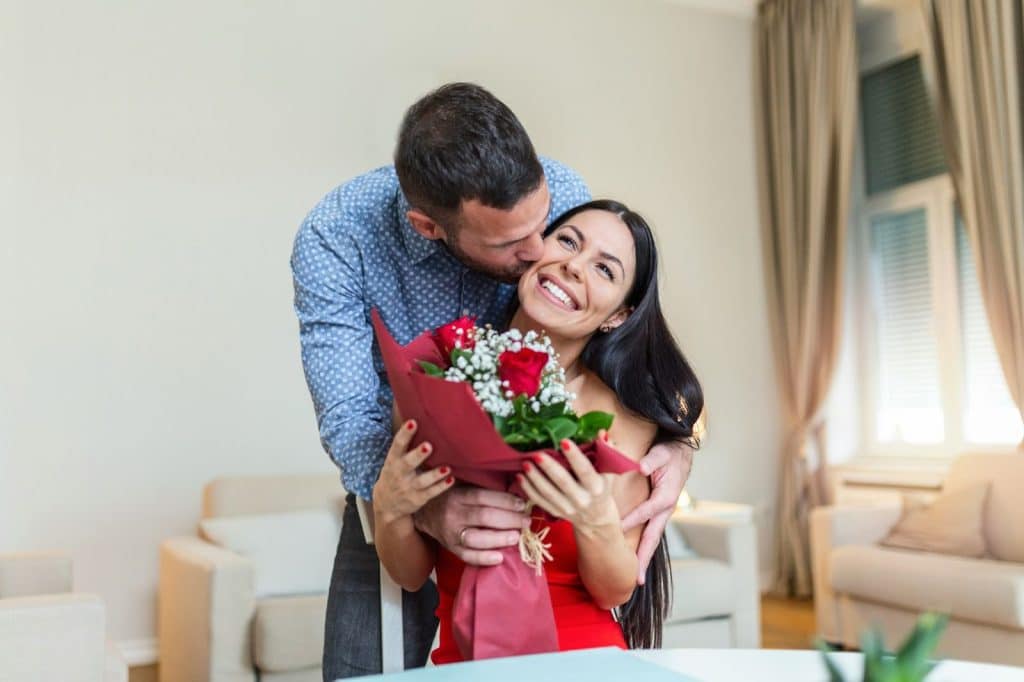 A man kissing a woman with flowers