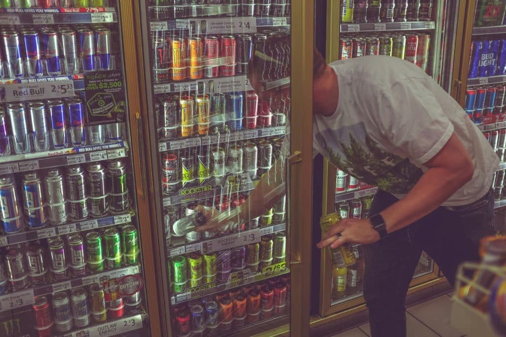 A man getting an energy drink from the fridge
